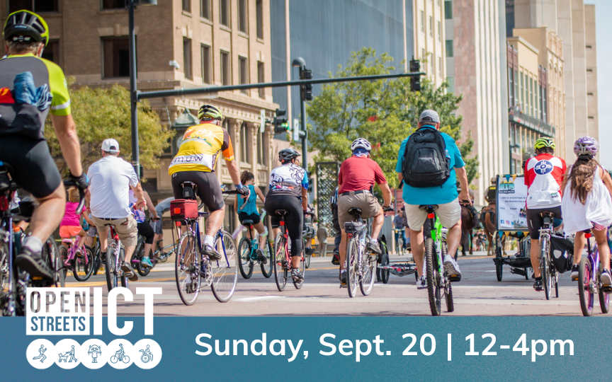 Group of cyclists participating in an open streets event, surrounded by urban buildings and trees on a sunny day.